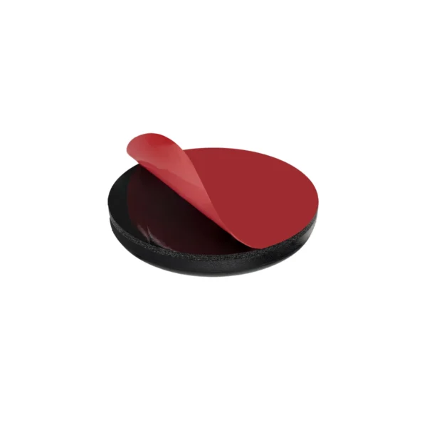 Round self-adhesive furniture slides, 38 mm (1.50"), black, peel-off liner being removed from the adhesive backing