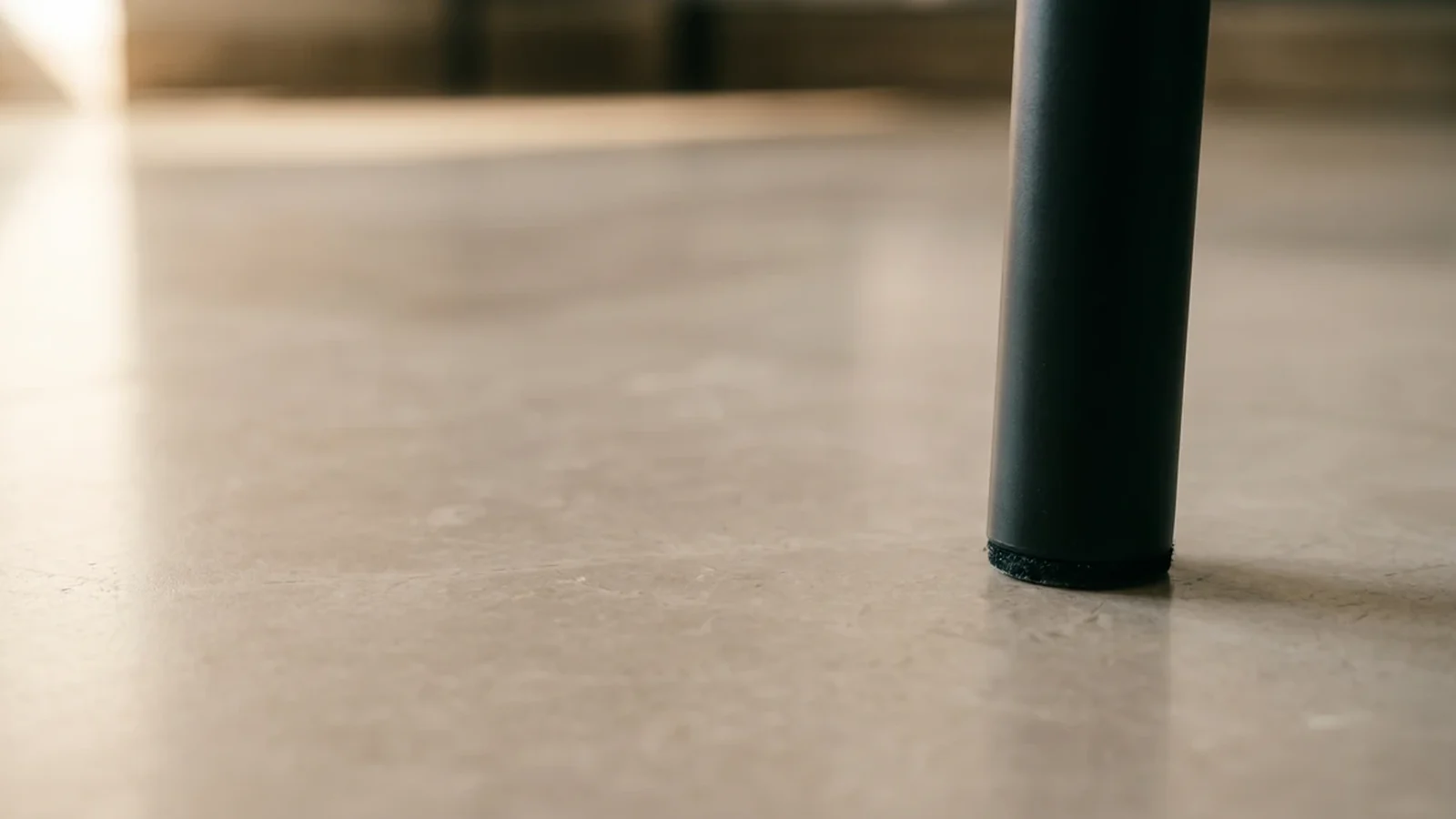 Furniture protector fitted to a metal table leg on a smooth stone tile floor