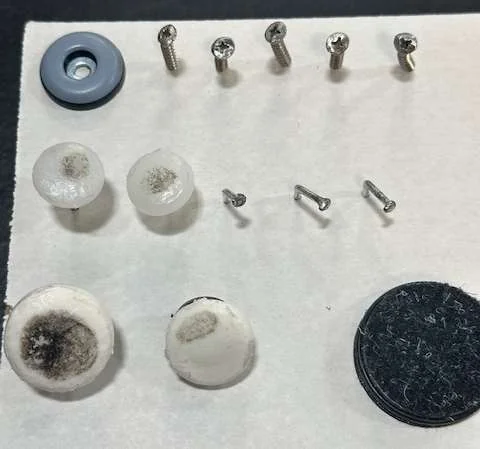 Four generations of glides removed from hotel lobby stools: PTFE slide, nail-on glides, soft plastic glides and the adhesive glide that replaced them